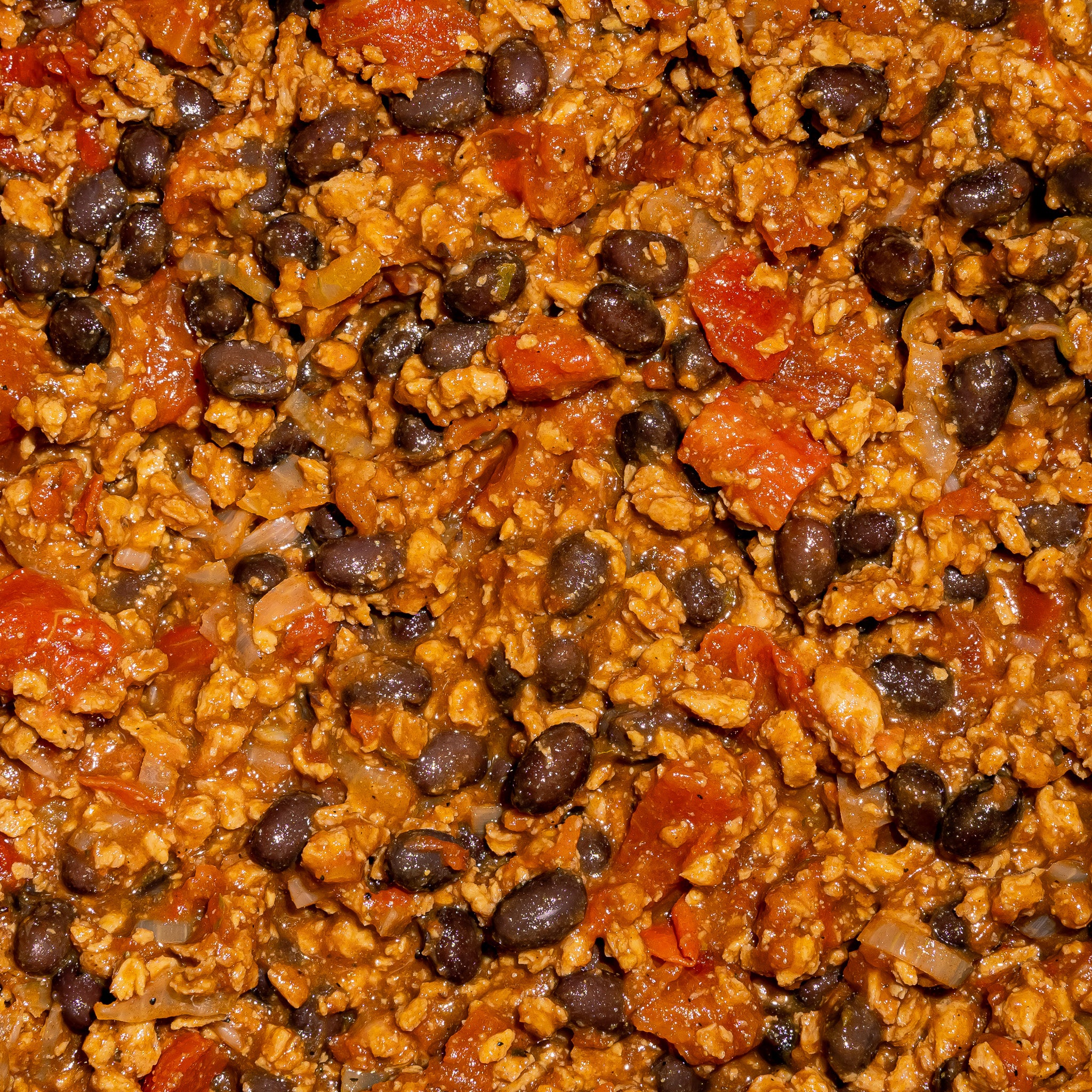 Gros plan sur un chili végétalien préparé avec la protéine Texmex de Grounded. Mélange savoureux de haricots noirs tomates oignons et protéine végétale de pois assaisonnée.