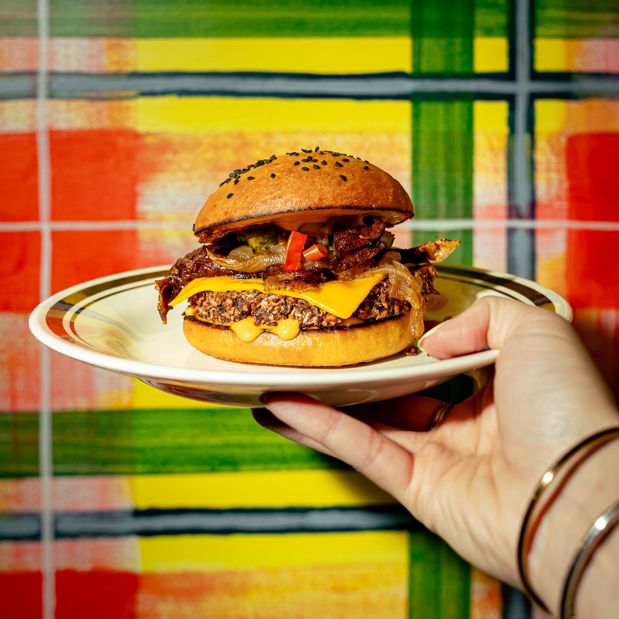 Burger végé créé en partenariat avec Loounie, servi dans une assiette avec une galette de PVT à base de protéines végétales, fromage, oignons caramélisés et sauce gourmande.