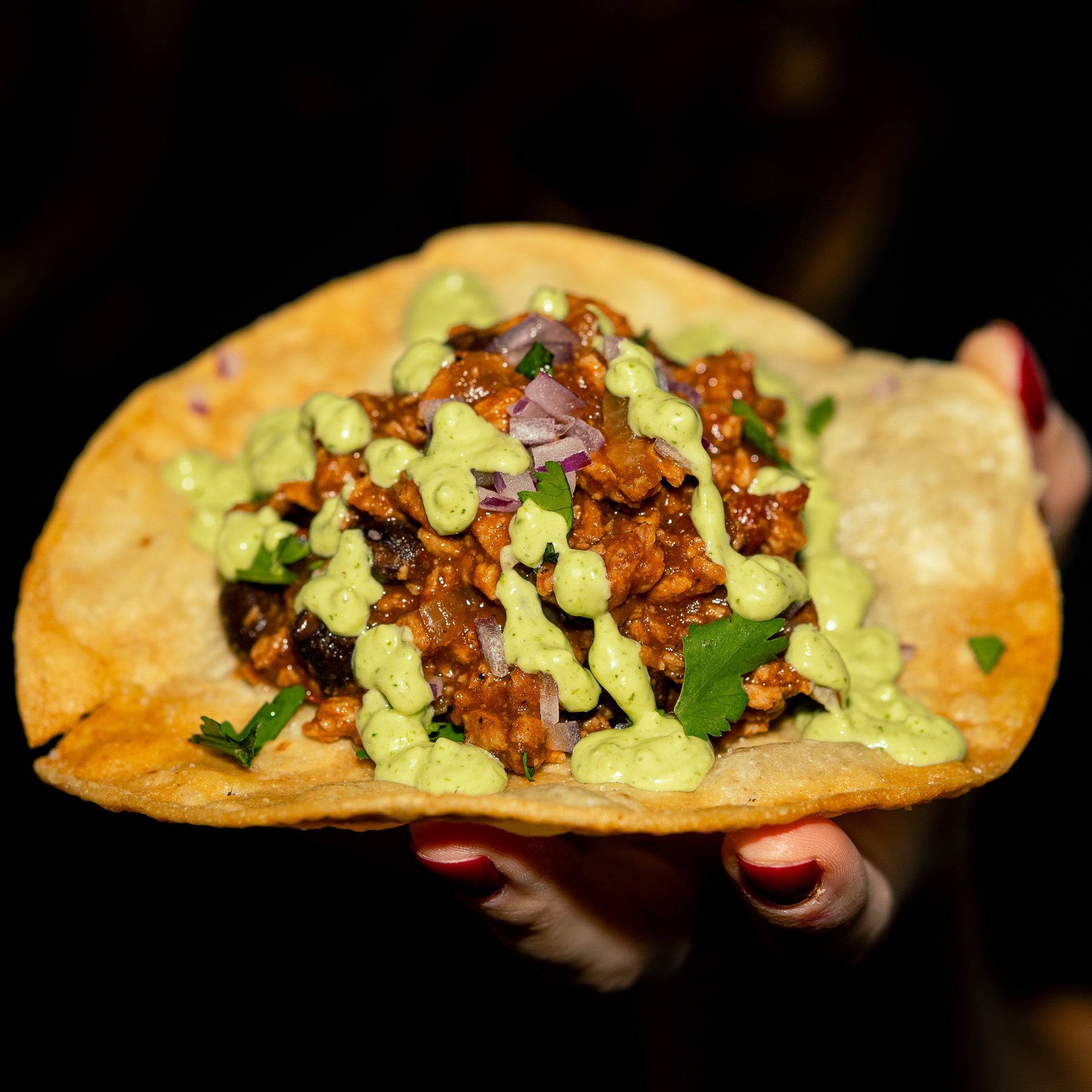 Taco croustillant garni de protéine Texmex Grounded oignons rouges coriandre et nappé d’une sauce verte crémeuse. Présenté en main prêt à déguster pour un repas végétalien savoureux et rapide.